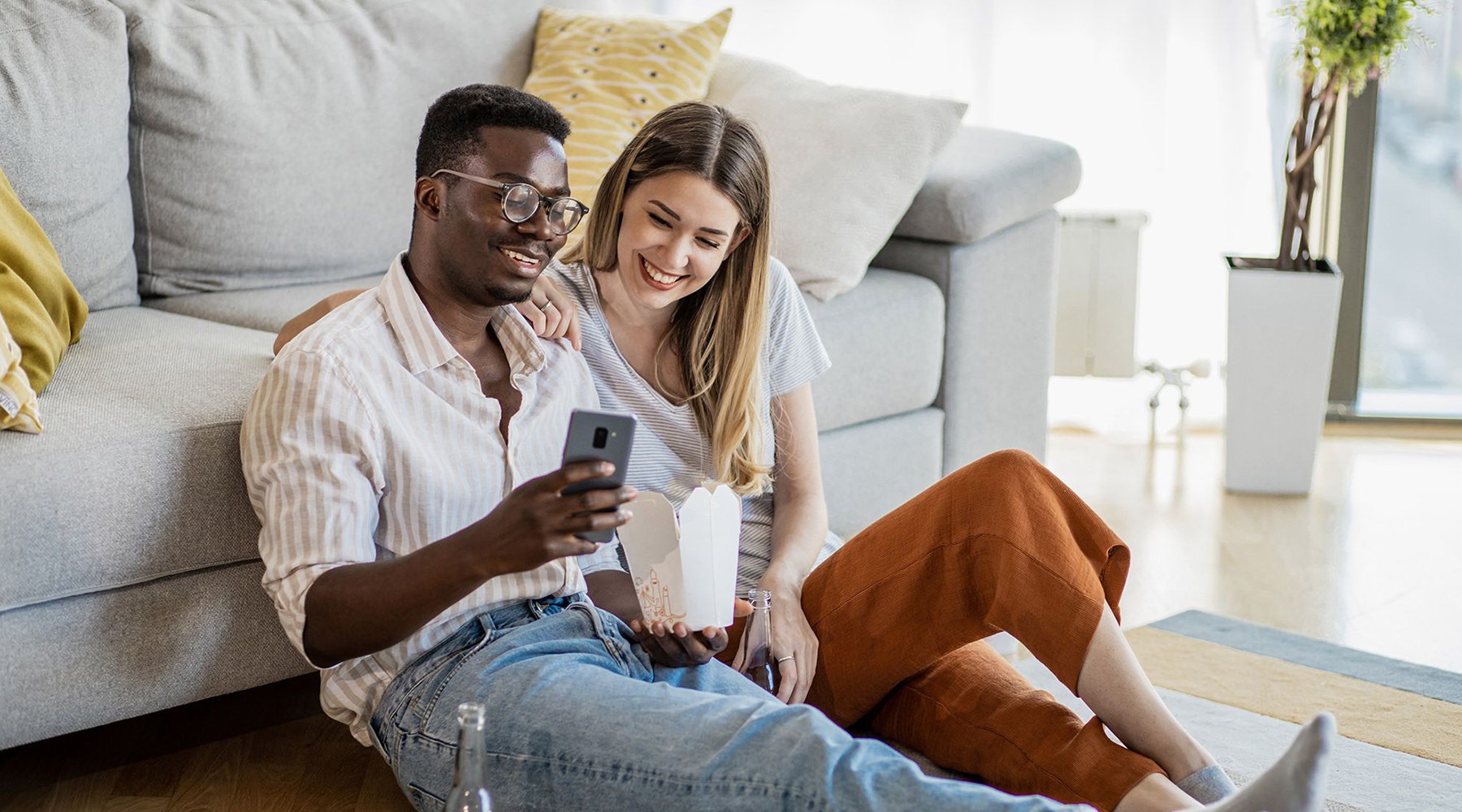 a couple sitting on the ground looking at a phone